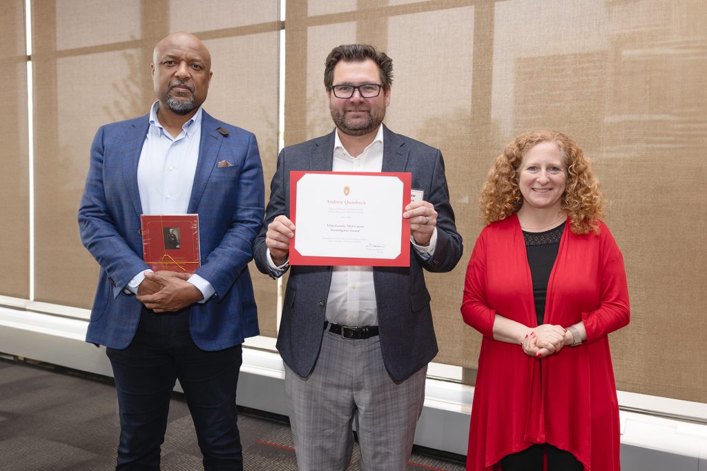 Dr. Andrew Quanbeck receiving an award and standing next to the Chancellor and Provost of UW-Madison